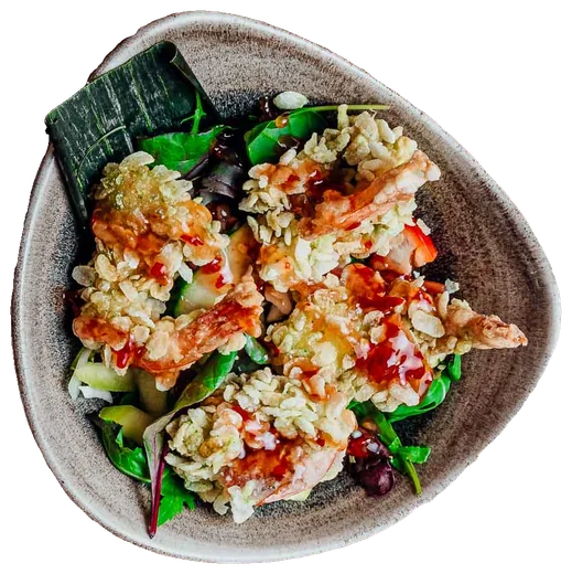 Garnelen in Reisflocken auf Salat in einer Steingutschale, von oben