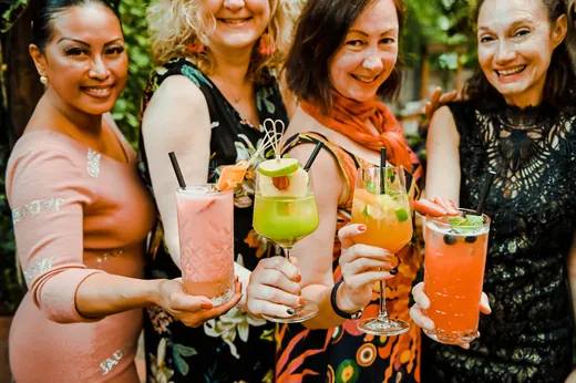 Vier Frauen stoßen mit bunten Cocktails an
