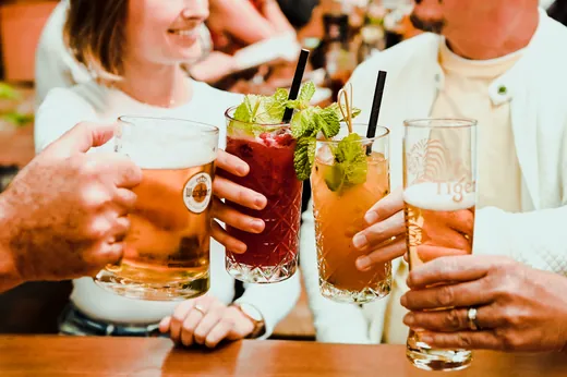 Hände halten Bier und Cocktails zum Anstoßen zusammen