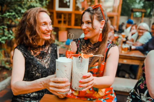 Zwei Frauen lachen und stoßen mit Limonaden an